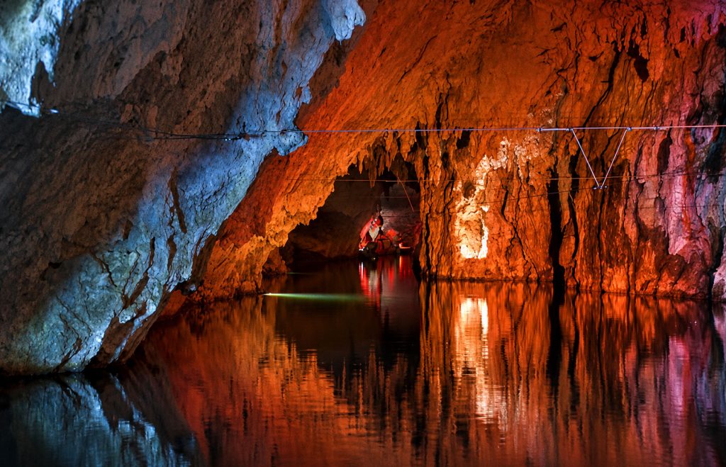 Interior of the Pertosa-Auletta Caves with the navigable underground river and evocative illuminated limestone formations.